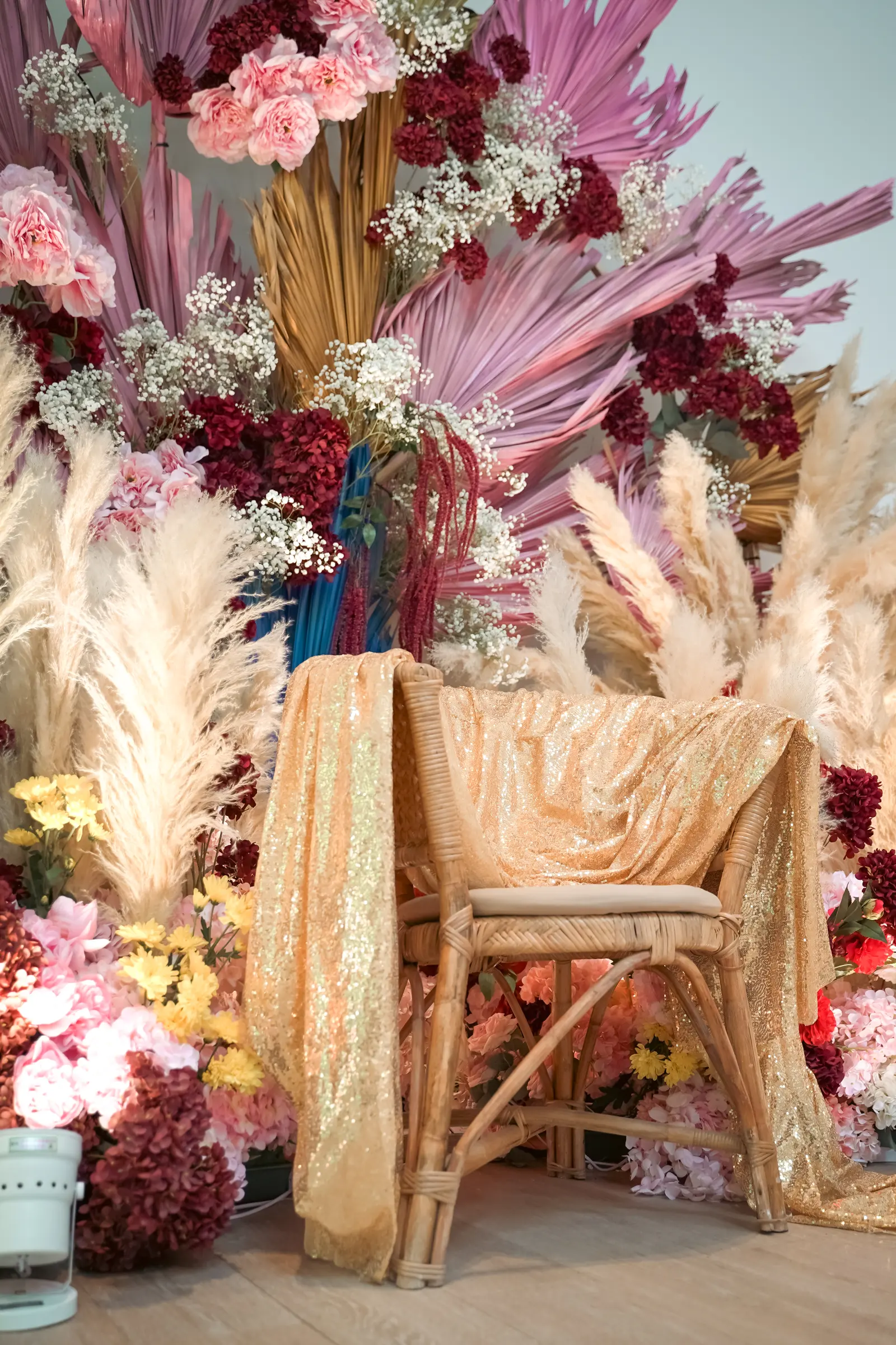 Layered floral décor and a gold-draped chair photographed at a hotel event