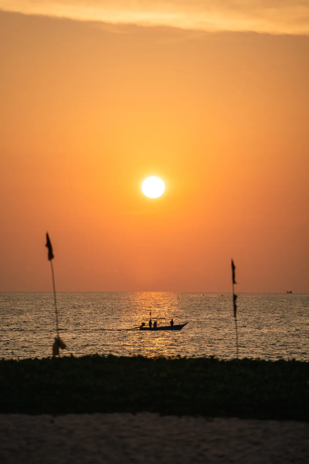 A boat silhouetted against an orange sunset over the sea