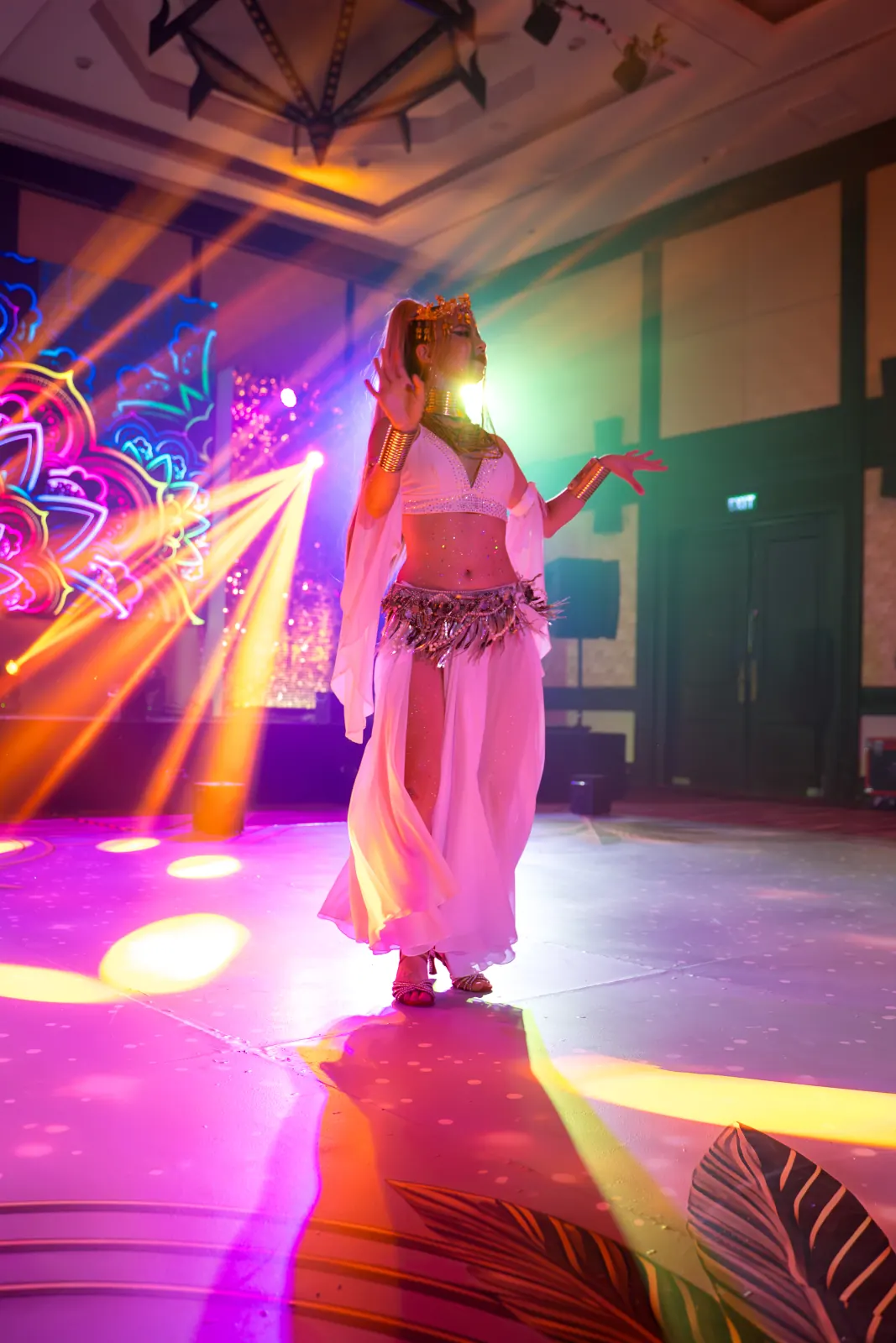 A costumed performer on stage under colourful event lighting