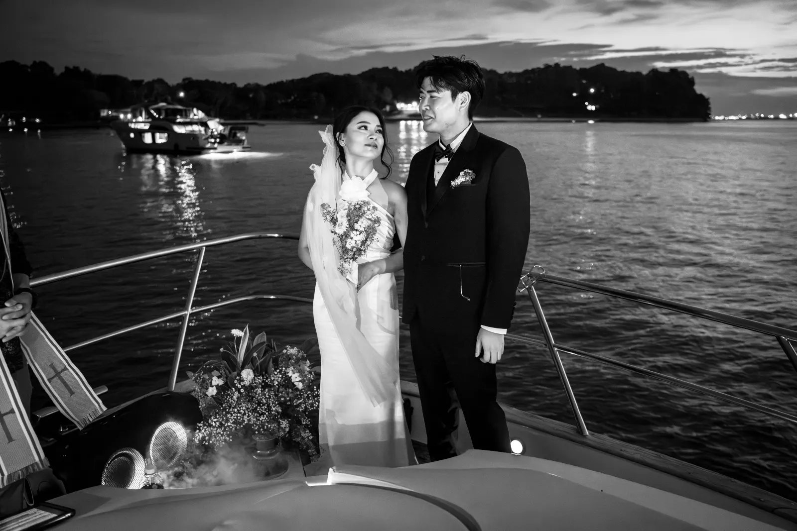 Newly married couple together at the front of a boat after dark
