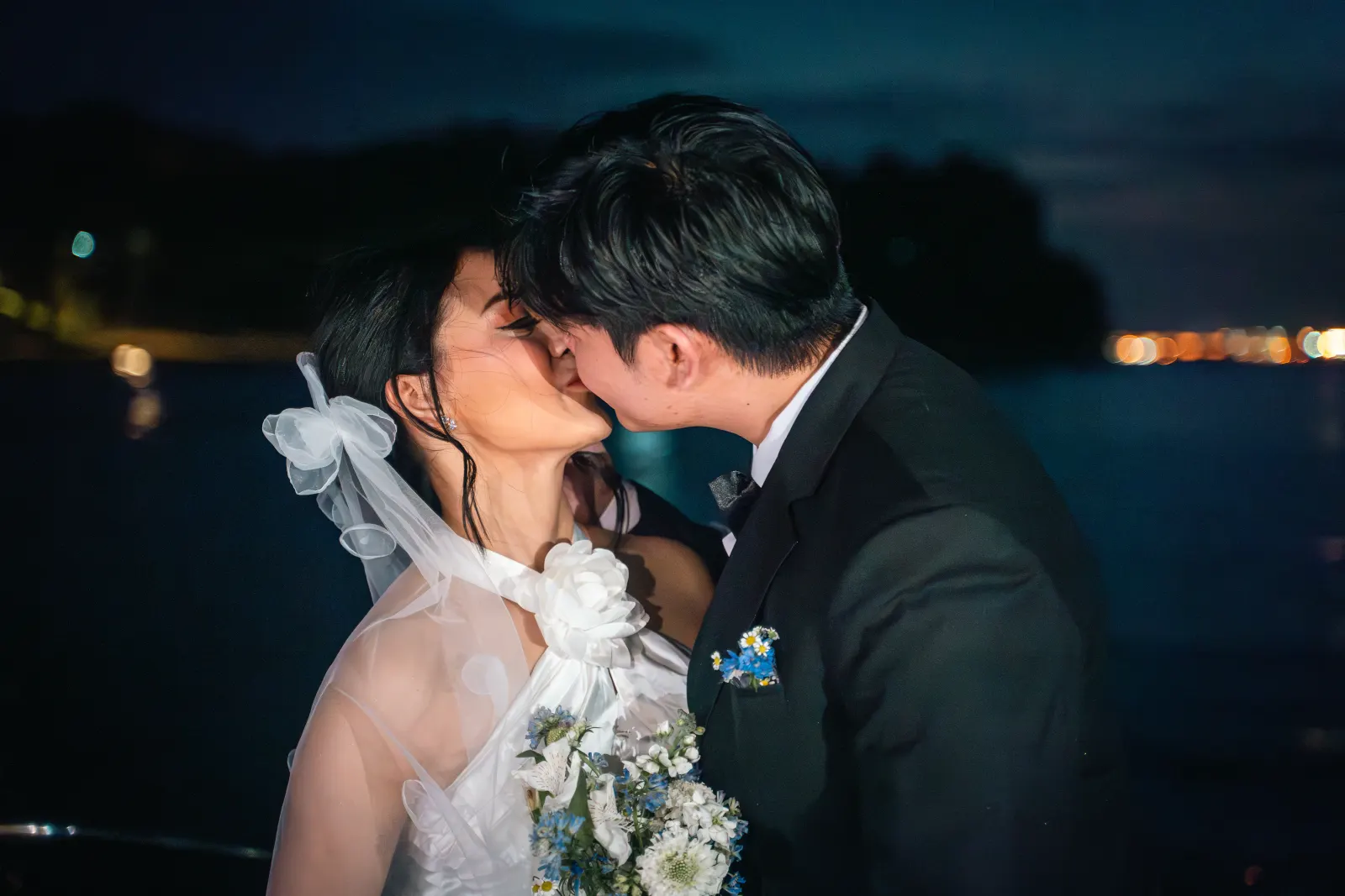 Newly married couple kissing during their evening boat celebration