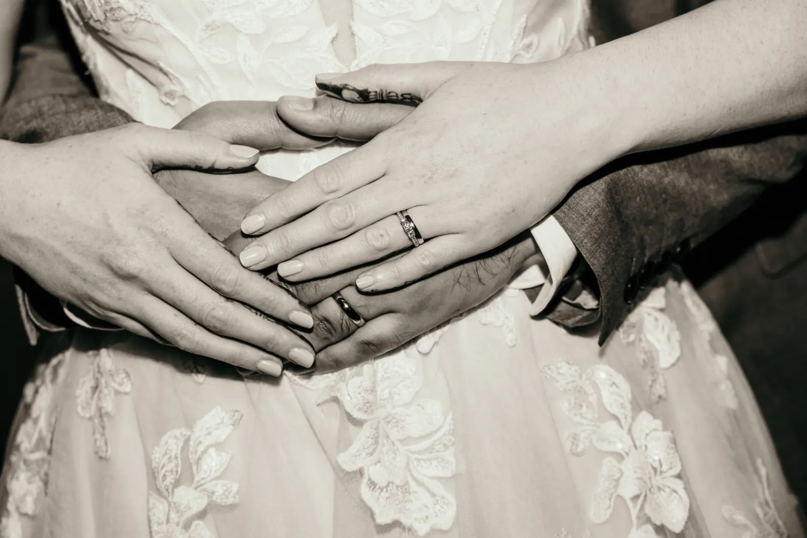 Black-and-white close-up of a newly married couple’s hands and rings